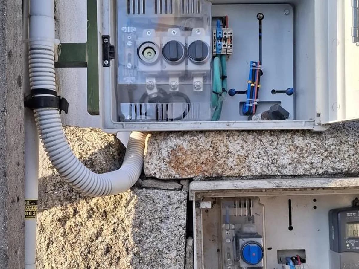 Caja general de protección abierta en la fachada de piedra de un edificio