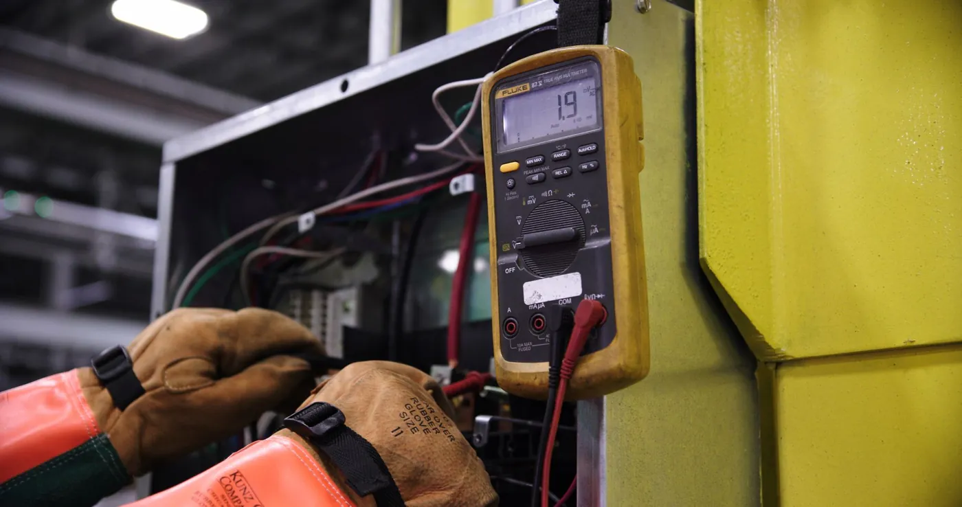 Electricista midiendo con el polímetro en un cuadro eléctrico abierto