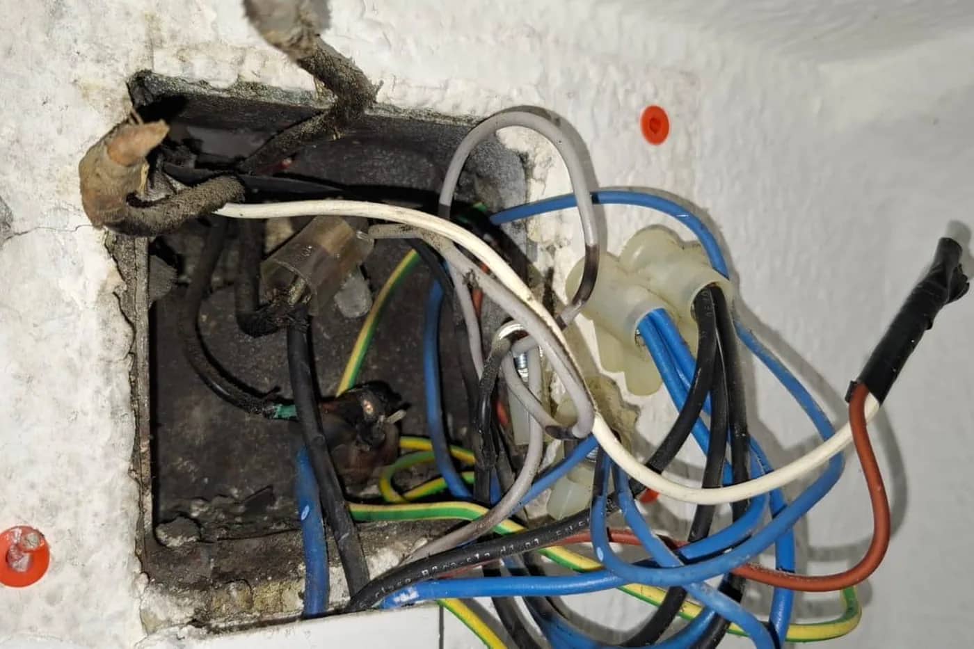 Caja de registro abierta con los empalmes enmarañados y suciedad acumulada